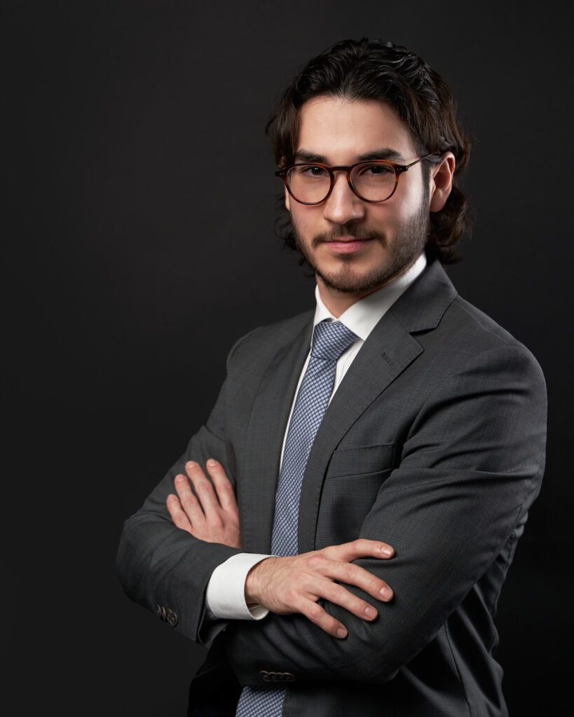 Retrato para LinkedIn de Joven con lentes y traje con corbata azul cruzado de brazos listo para su fotografía perfil profesional