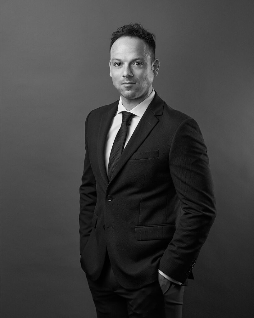 hombre con traje y corbata parado a 45 grados con la vista al frente toma en blanco y negro. Fotografía para Branding Personal