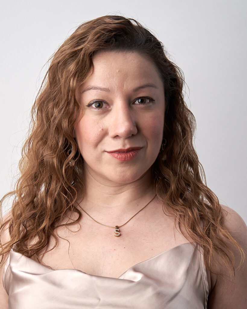 Mujer de cabello castaño ondulado mirando con la cara ligeramente hacia su izquierda y expresión seria. Ejemplo de Foto Perfil LinkedIn para no Fotogénicos
