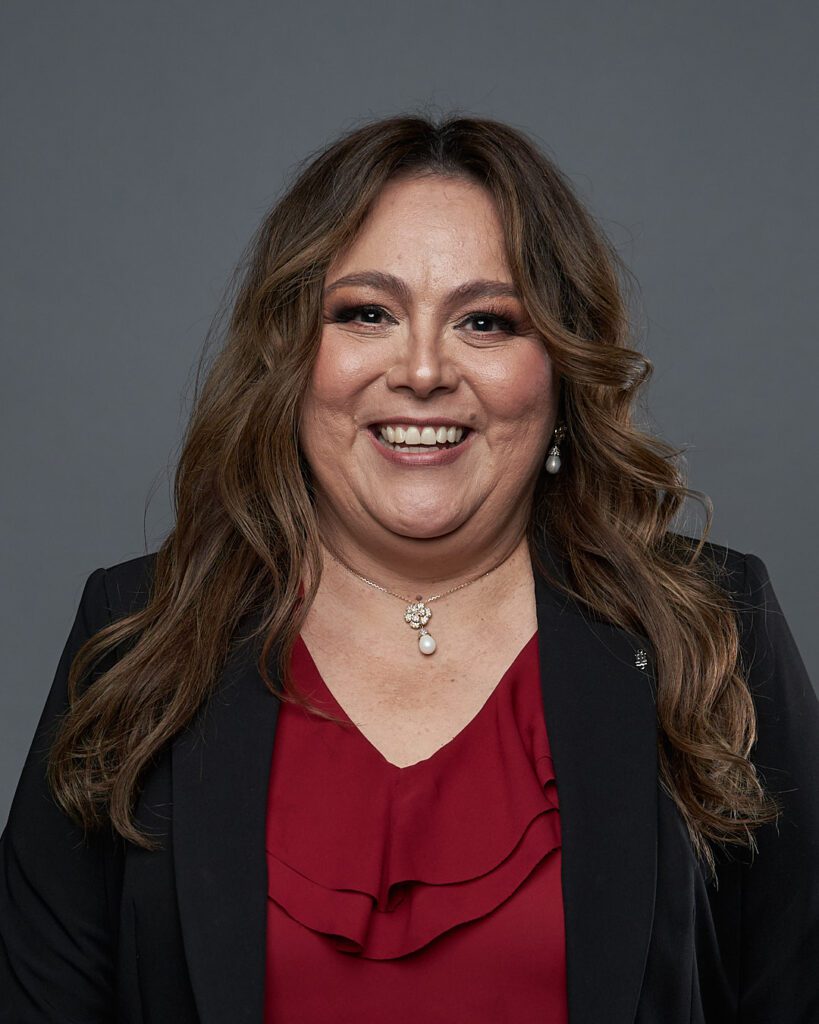 Ejemplo de Foto Perfil LinkedIn para no Fotogénicos de Mujer de cabello castaño ondulado mirando con la cara sonriente mirando a la cámara con la cara hacia adentro mostrando cuello ancho y papada.